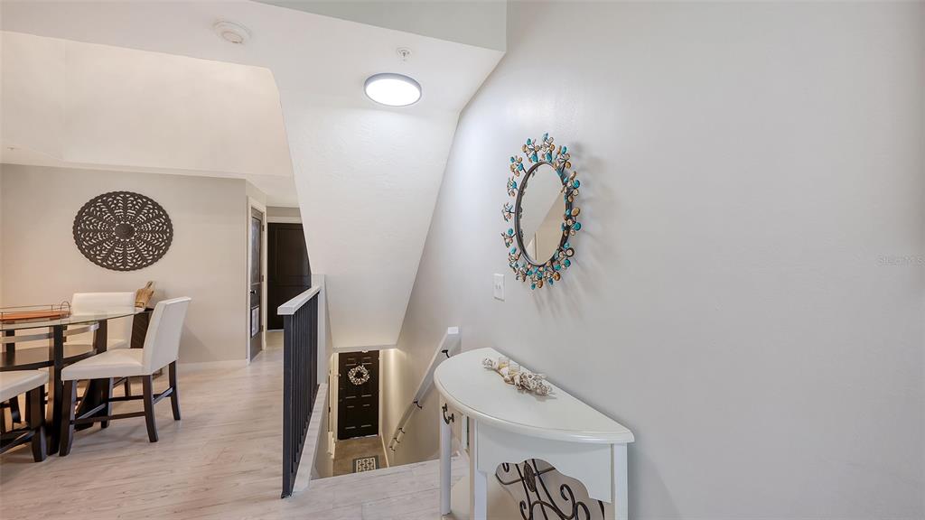 A white console table sits in a hallway next to a staircase and dining area — 5655 BENTGRASS DRIVE UNIT 9-116, SARASOTA, FL
