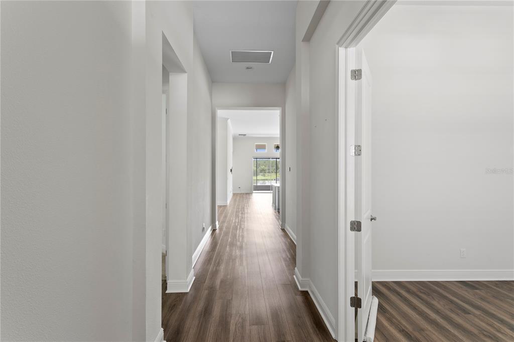 A hallway with wood-look flooring leads toward an open living area with a view outside — 2160 SECRET COVE, ODESSA, FL