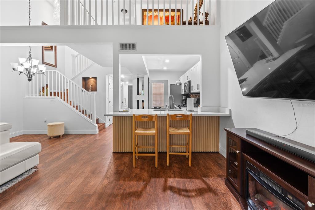 A living room with a kitchen pass-through, breakfast bar, and staircase with white railings — 1215 NW 55TH STREET NW UNIT 7, GAINESVILLE, FL