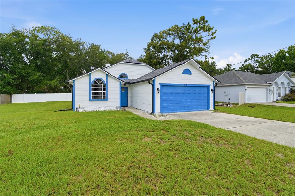 A white single-story house with blue trim, a blue garage door, and a large front lawn — 1238 COURTLAND BOULEVARD, DELTONA, FL