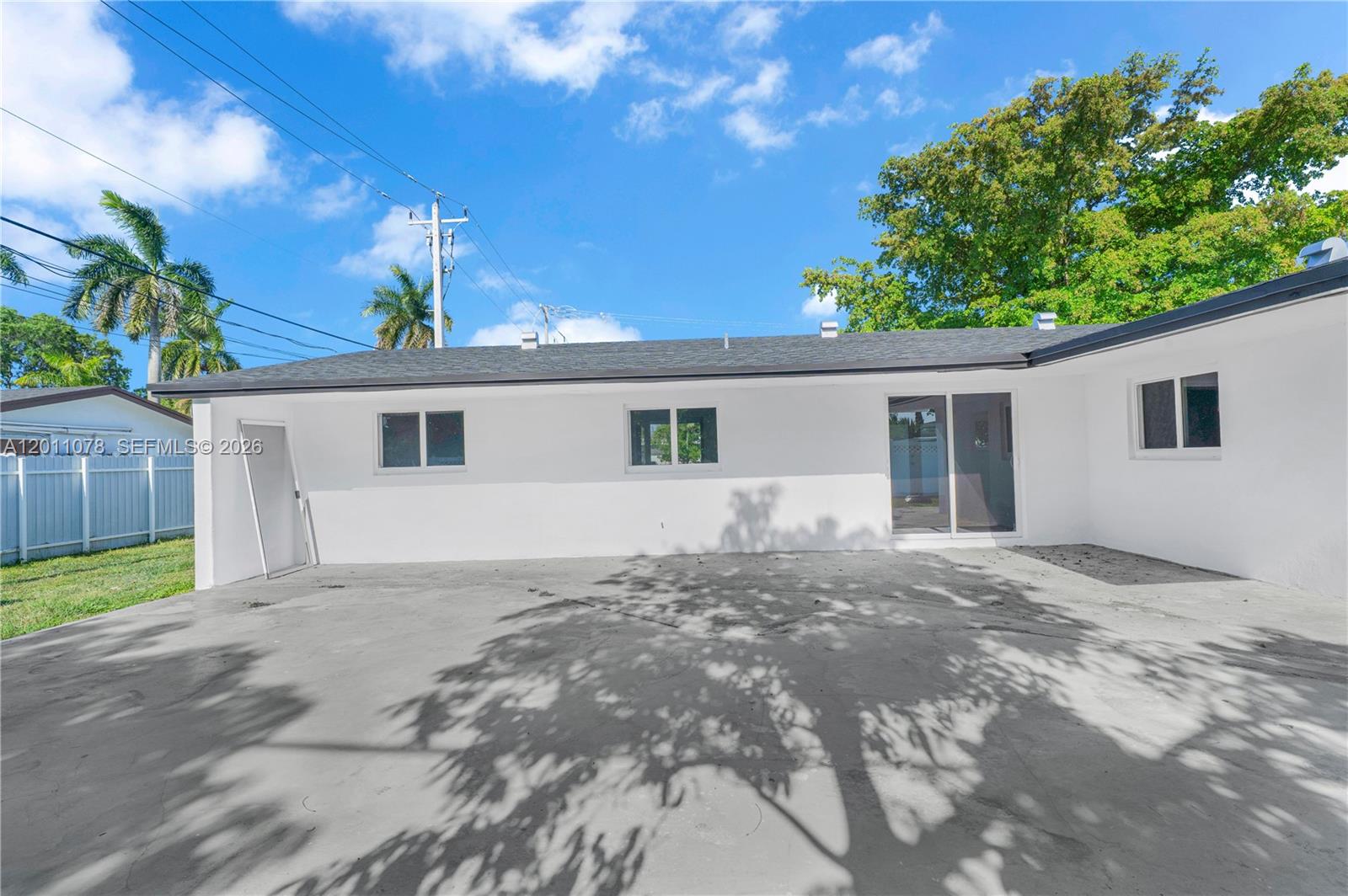 The exterior of a white house features a concrete patio, sliding glass doors, and windows — 17850 SW 112th Ave, Miami FL 33157, MIAMI, FL