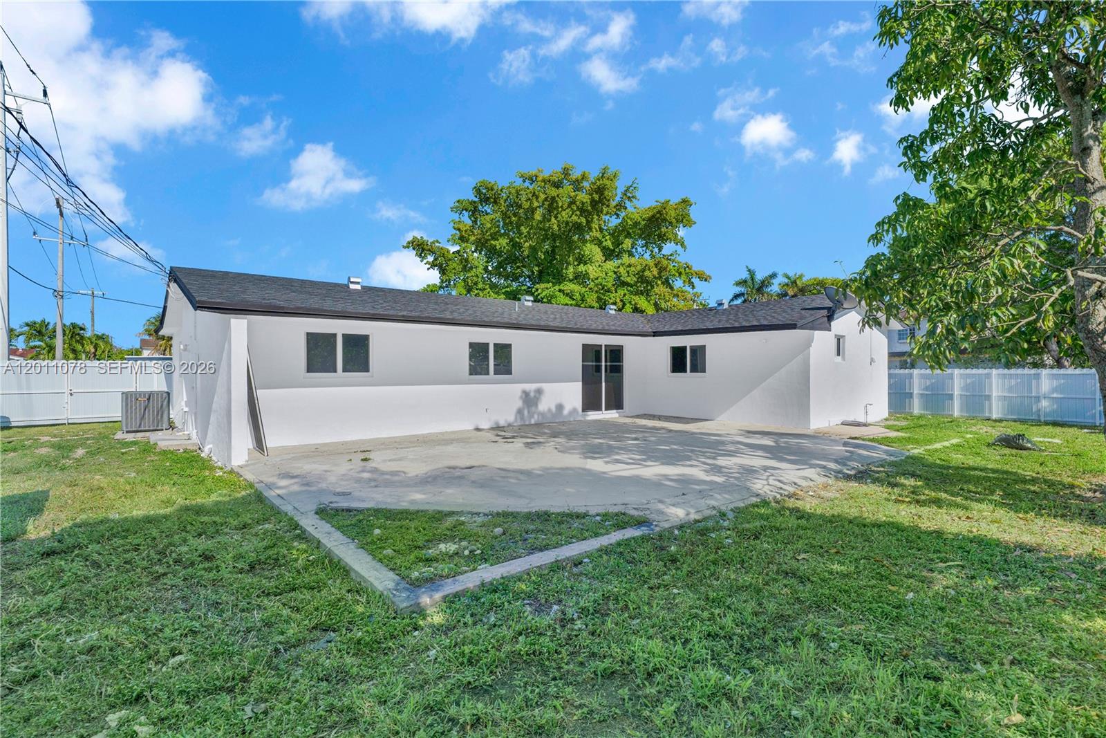 The back of a white house features a concrete patio and a dark roof — 17850 SW 112th Ave, Miami FL 33157, MIAMI, FL