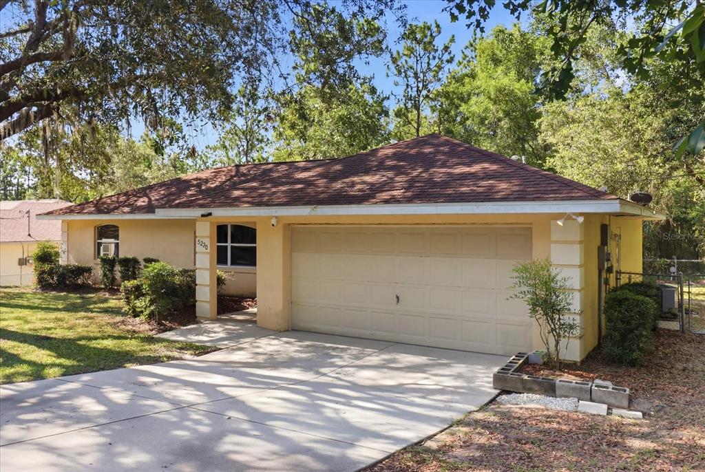 A single-story house with a tan stucco exterior, a brown shingled roof, and a garage — 3220 E ROGERS STREET, INVERNESS, FL