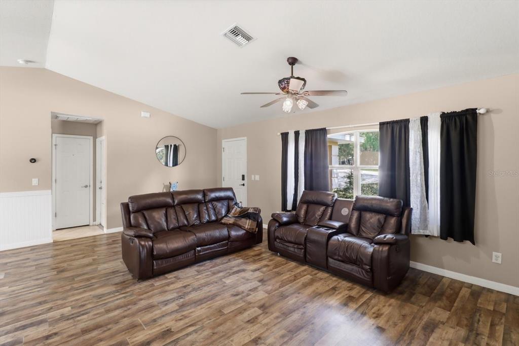 A living room features brown leather furniture, wood-look flooring, and a ceiling fan — 3220 E ROGERS STREET, INVERNESS, FL