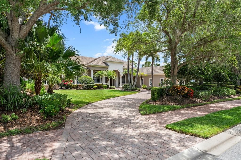 A paved driveway leads to the front entrance of a single-story house with landscaping — 4085 FOUNDERS CLUB DRIVE, SARASOTA, FL