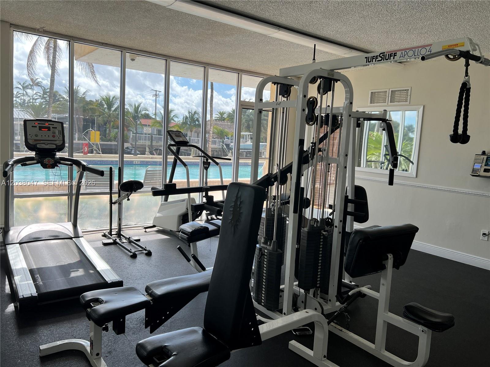 A lobby area features two blue armchairs, a wooden console table, and mirrored walls — 2350 NE 135th St # 704, North Miami FL 33181, NORTH MIAMI, FL