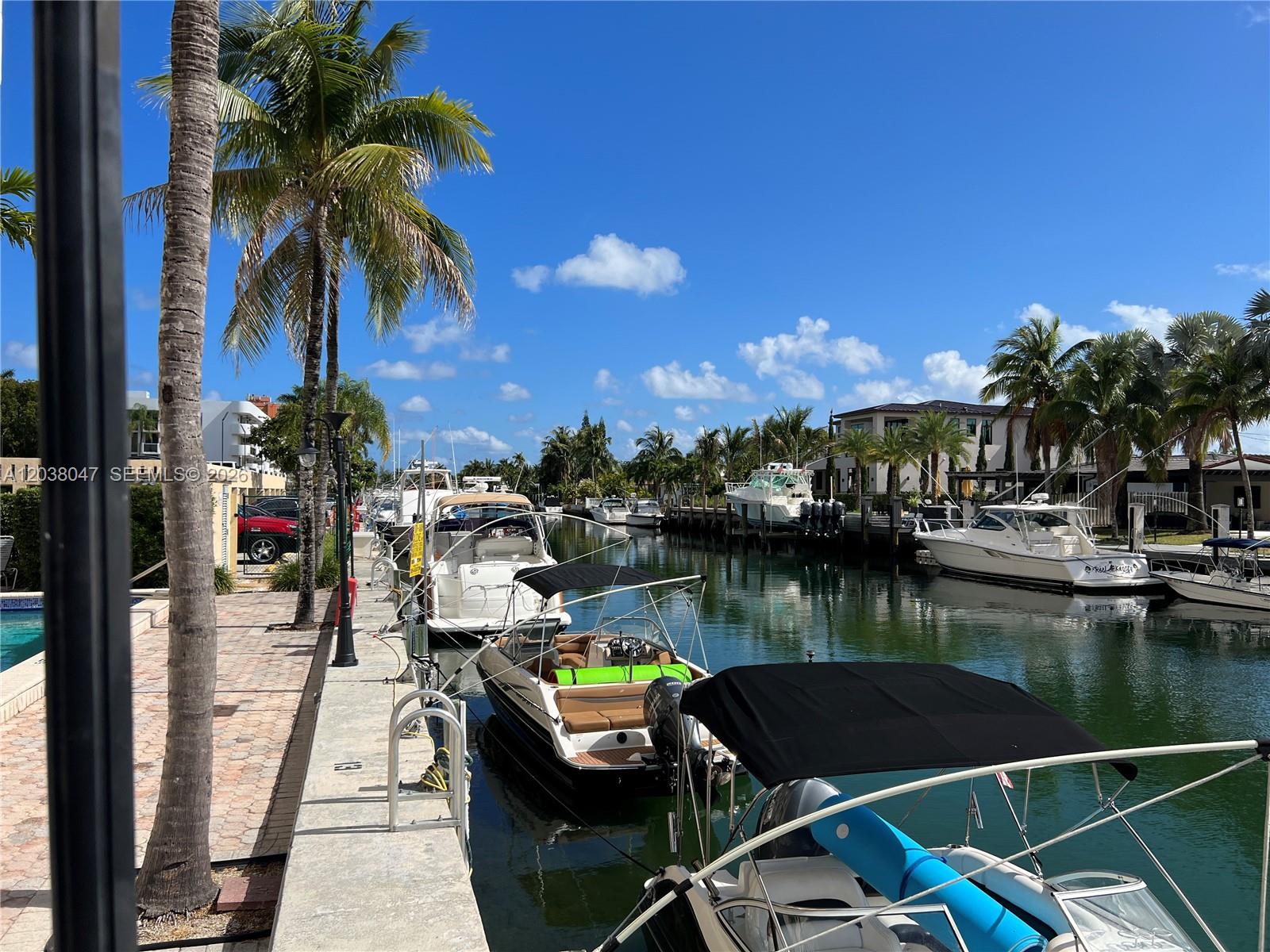 A gym with exercise equipment overlooks a swimming pool through large floor-to-ceiling windows — 2350 NE 135th St # 704, North Miami FL 33181, NORTH MIAMI, FL