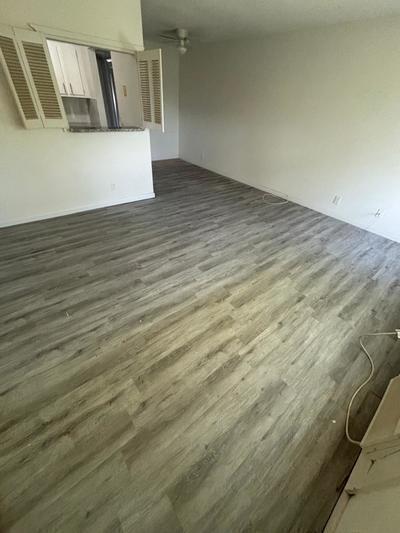 An empty living room features light gray wood-look flooring and a pass-through window to the kitchen — 244 Windsor K, West Palm Beach FL 33417, WEST PALM BEACH, FL