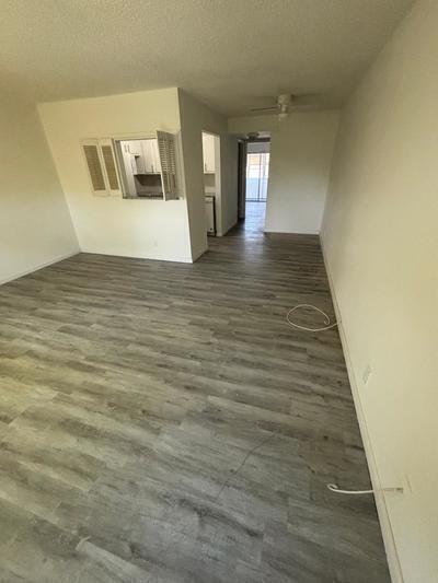 An empty living room features light gray wood-look flooring and a pass-through window to the kitchen — 244 Windsor K, West Palm Beach FL 33417, WEST PALM BEACH, FL