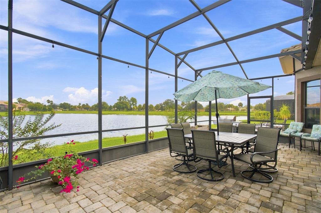 A screened-in patio with a dining set overlooks a lake and grassy landscape — 970 SAN RAPHAEL STREET, POINCIANA, FL