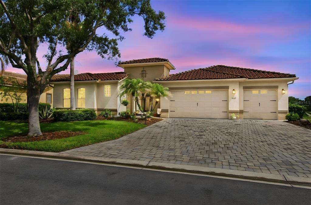 A single-story house with a tile roof, three-car garage, and a paved driveway at sunset — 970 SAN RAPHAEL STREET, POINCIANA, FL