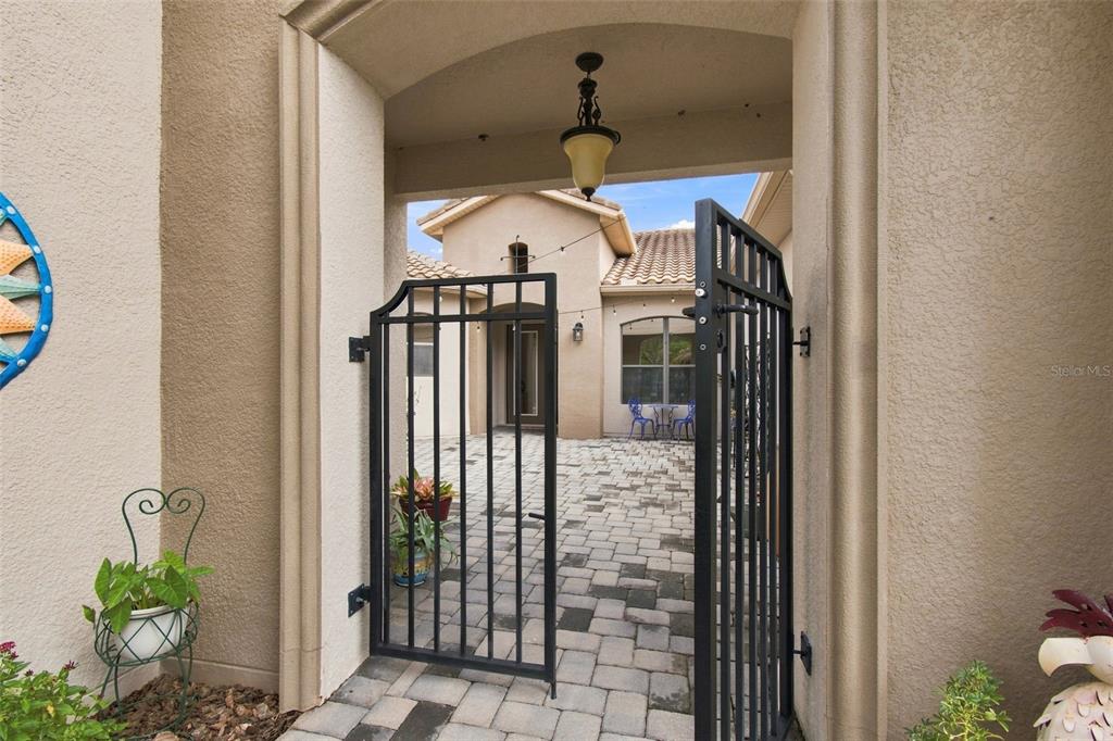 A gated entryway leads to a paved courtyard in front of a stucco home — 970 SAN RAPHAEL STREET, POINCIANA, FL