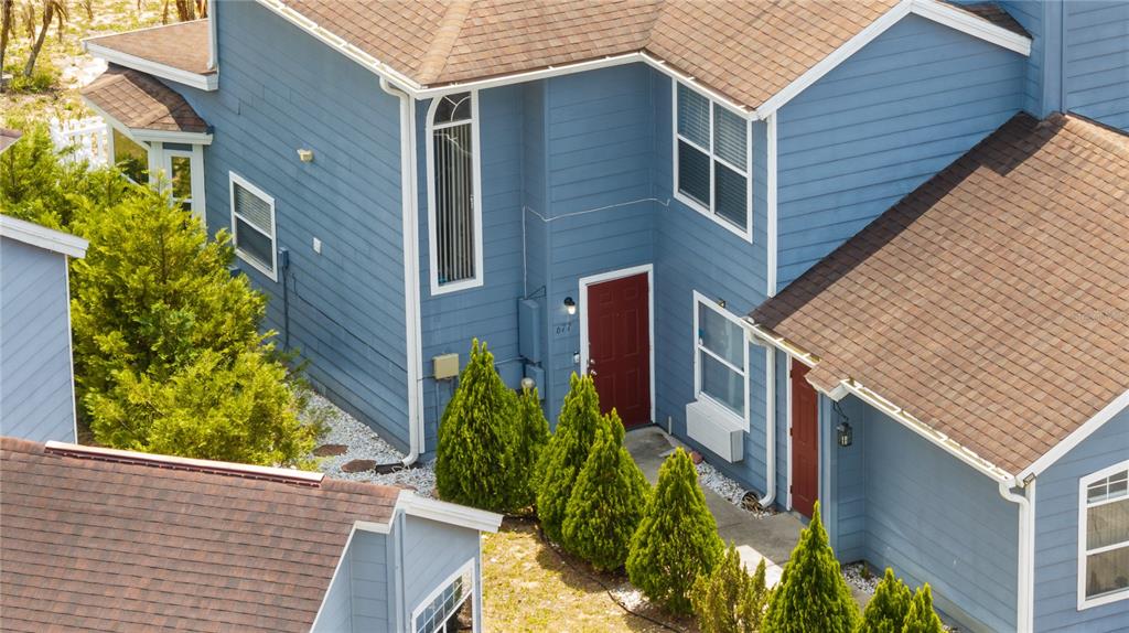 An aerial view shows the blue-sided exterior of a two-story building with red doors — 677 ORCHID DRIVE, DAVENPORT, FL