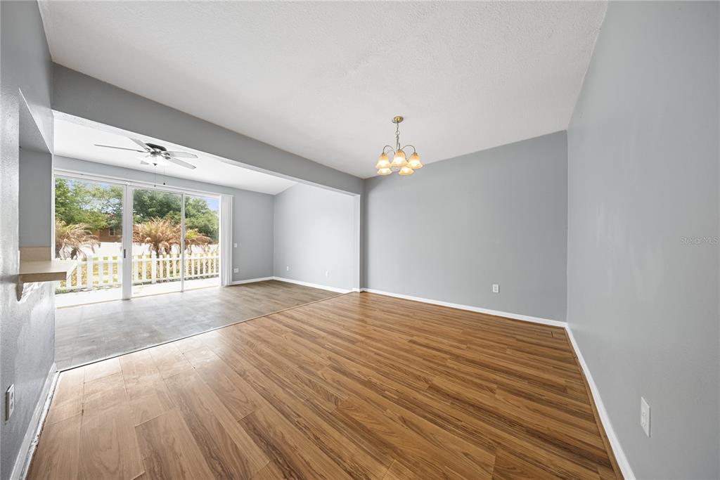 An empty dining room with wood-look flooring, a chandelier, and a sliding glass door — 677 ORCHID DRIVE, DAVENPORT, FL