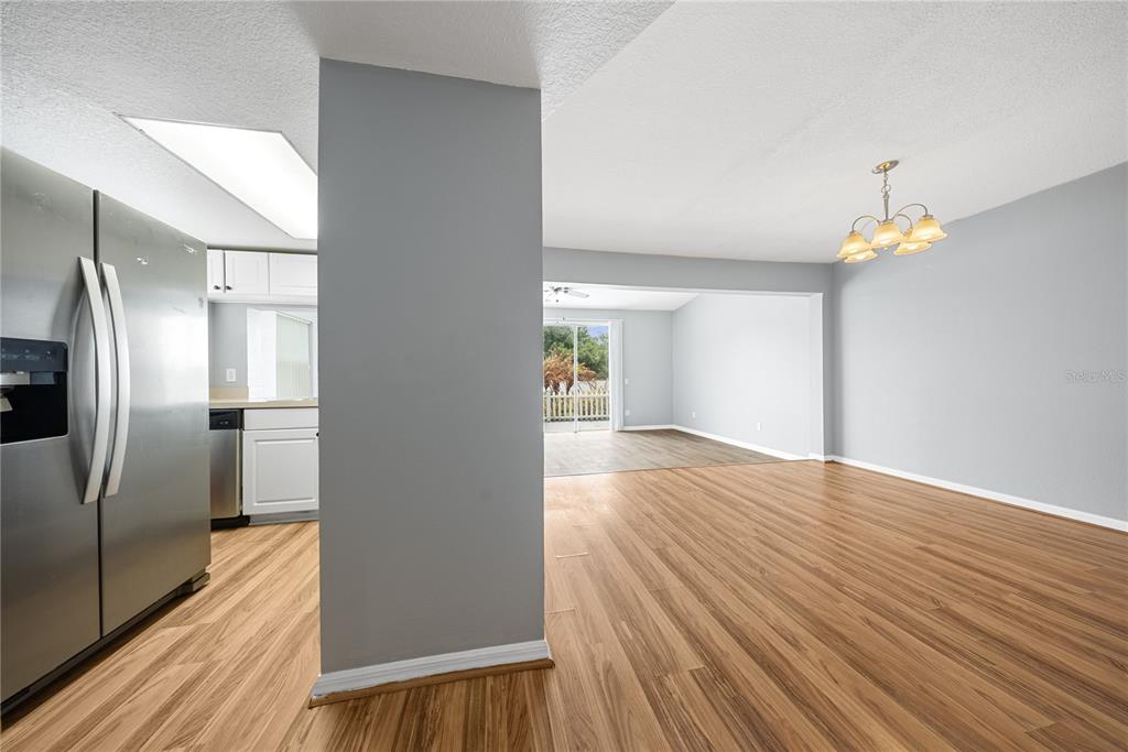A view from a kitchen toward a dining area and a living room with wood flooring — 677 ORCHID DRIVE, DAVENPORT, FL