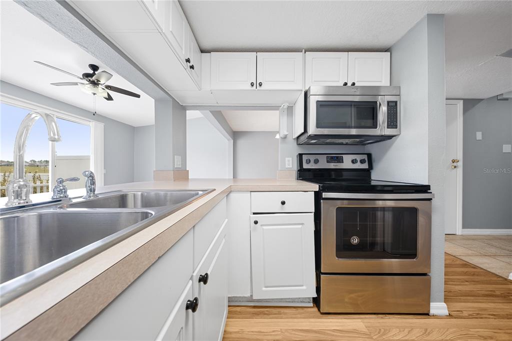 A kitchen features white cabinets, stainless steel appliances, and a double sink with laminate countertops — 677 ORCHID DRIVE, DAVENPORT, FL