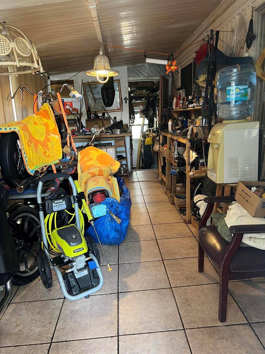 A cluttered sunroom or garage with tile flooring, a water cooler, and various stored items — 313 NW 48th Court, Pompano Beach FL 33064, POMPANO BEACH, FL