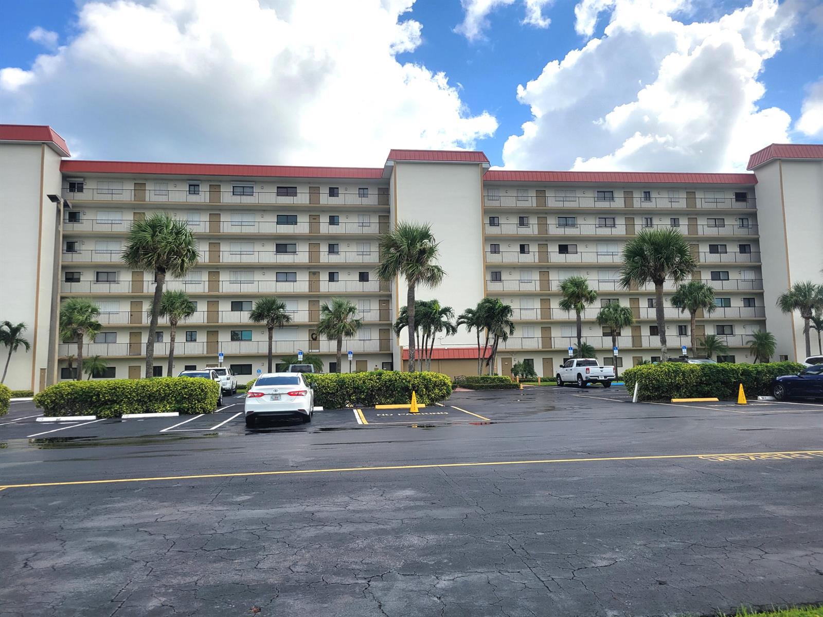 A multi-story apartment building with a red roof and palm trees in a parking lot — 10152 S Ocean Drive # 418b, Jensen Beach FL 34957, JENSEN BEACH, FL