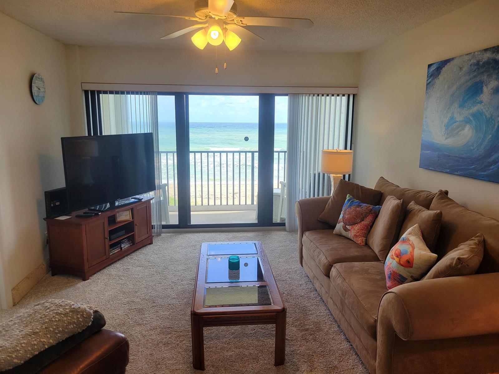 A living room with a brown sofa, coffee table, television, and a balcony overlooking the ocean — 10152 S Ocean Drive # 418b, Jensen Beach FL 34957, JENSEN BEACH, FL