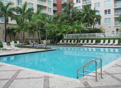 A swimming pool with lounge chairs and palm trees in front of a multi-story building — 2000 N Bayshore Dr # 122, Miami FL 33137, MIAMI, FL