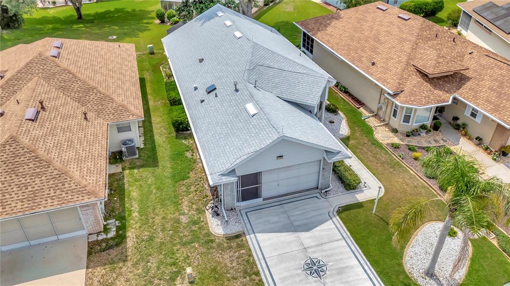 An aerial view shows a house with a gray roof between two brown-roofed homes — 21707 QUEEN MARY COURT, LEESBURG, FL