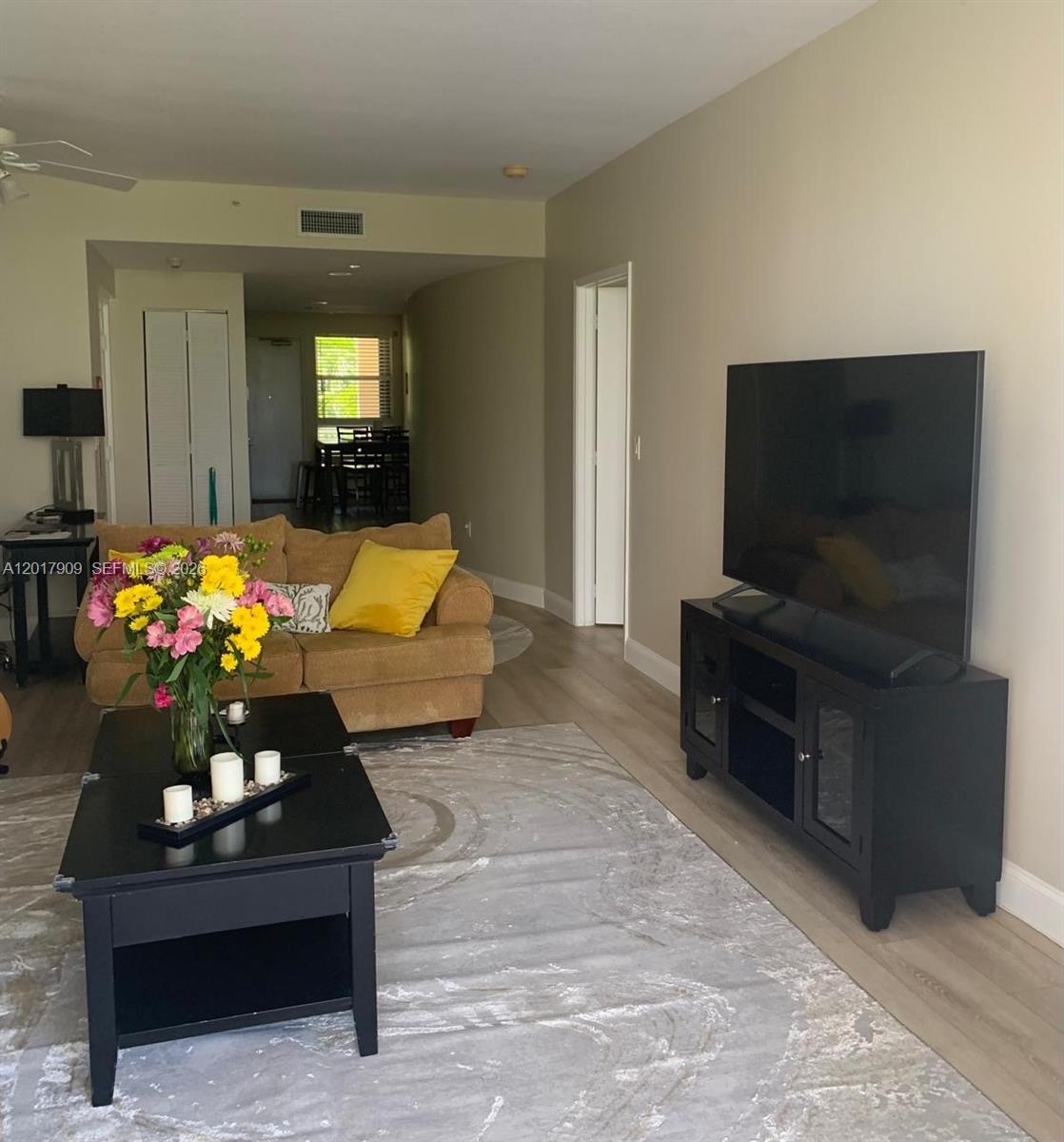A living room features a tan sofa, a black coffee table, and a television stand — 717 Crandon Blvd # 408, Key Biscayne FL 33149, KEY BISCAYNE, FL