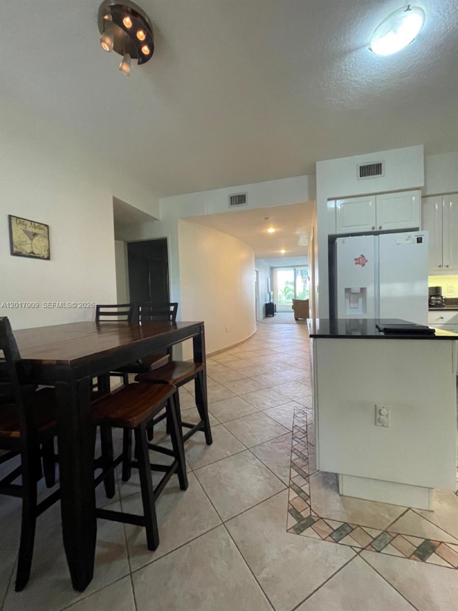 A dining area with a wooden table and chairs sits next to a white kitchen — 717 Crandon Blvd # 408, Key Biscayne FL 33149, KEY BISCAYNE, FL