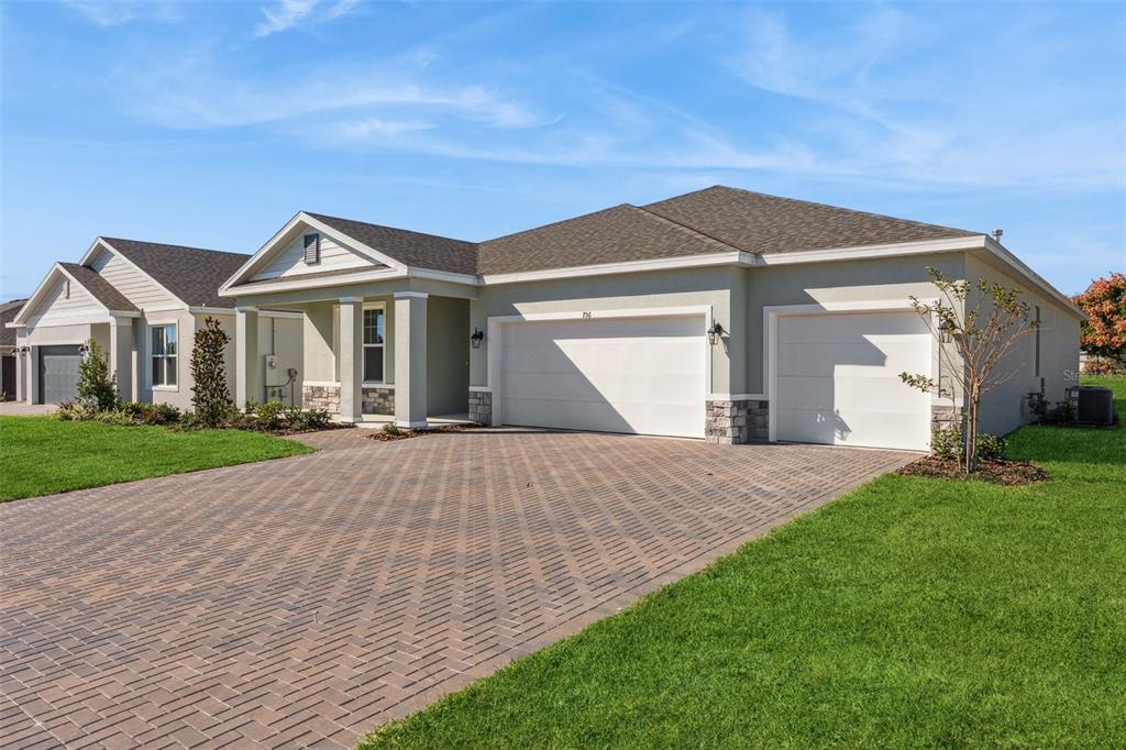 A single-story house with a three-car garage and a paved driveway under a blue sky — 574 EMERALD GROVE DRIVE, APOPKA, FL