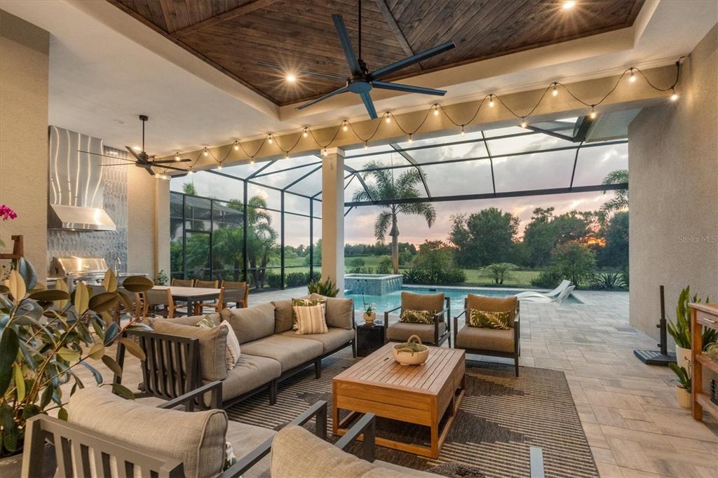 A covered outdoor patio features a pool, lounge seating, dining area, and wood-paneled ceiling — 8254 PAVIA WAY, LAKEWOOD RANCH, FL