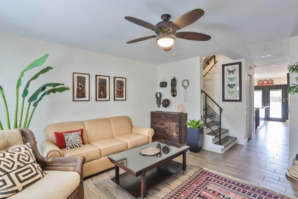 A living room features a tan sofa, glass coffee table, ceiling fan, and a staircase — 3355 W WYOMING CIRCLE, TAMPA, FL