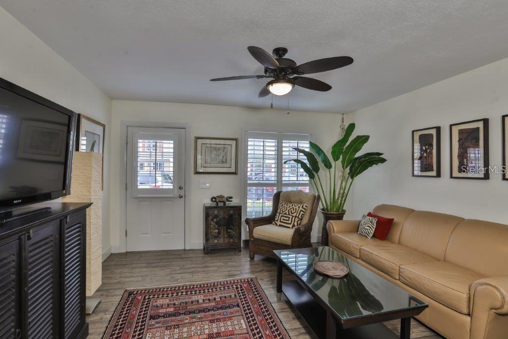 A living room features a tan leather sofa, a patterned rug, and a ceiling fan — 3355 W WYOMING CIRCLE, TAMPA, FL