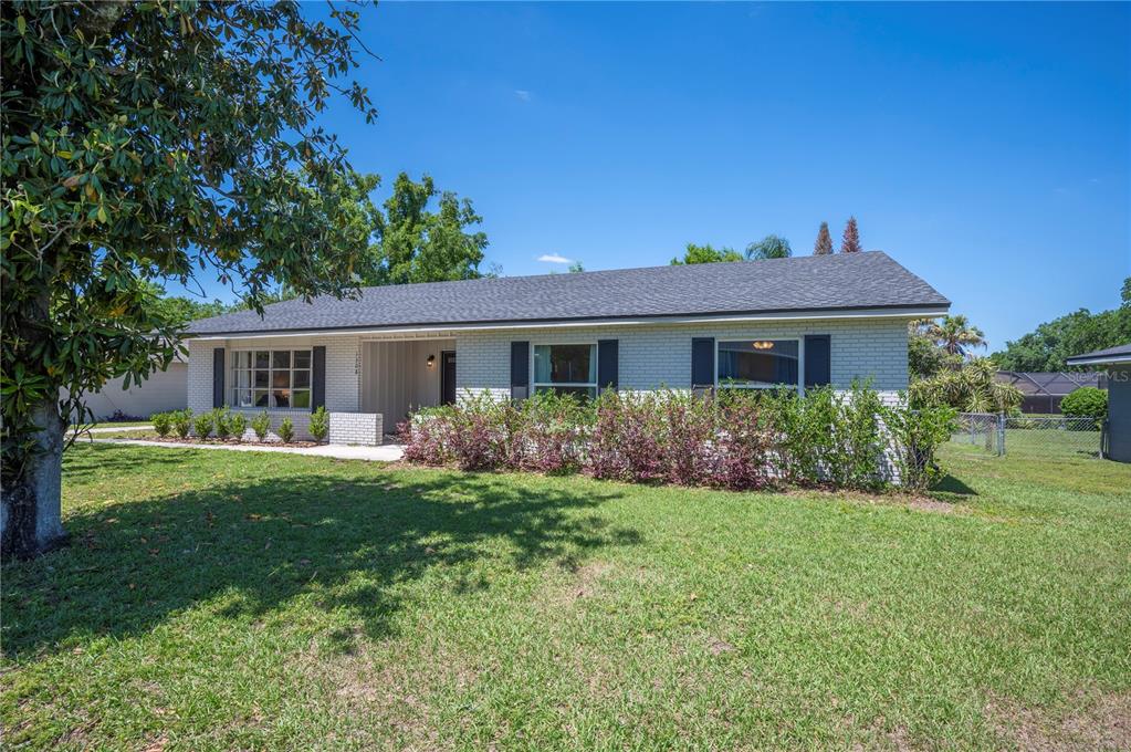 A single-story white brick house with a dark shingled roof and a front lawn — 1308 GLENFORD LANE, LAKELAND, FL