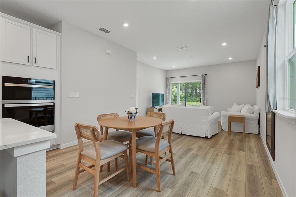 A dining area with a round wooden table sits adjacent to a living room — 1303 RIBBON PLACE, PALM COAST, FL