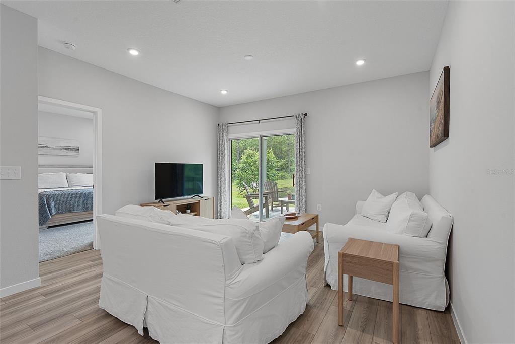 A living room with white sofas, a television, and a sliding glass door to a patio — 1303 RIBBON PLACE, PALM COAST, FL