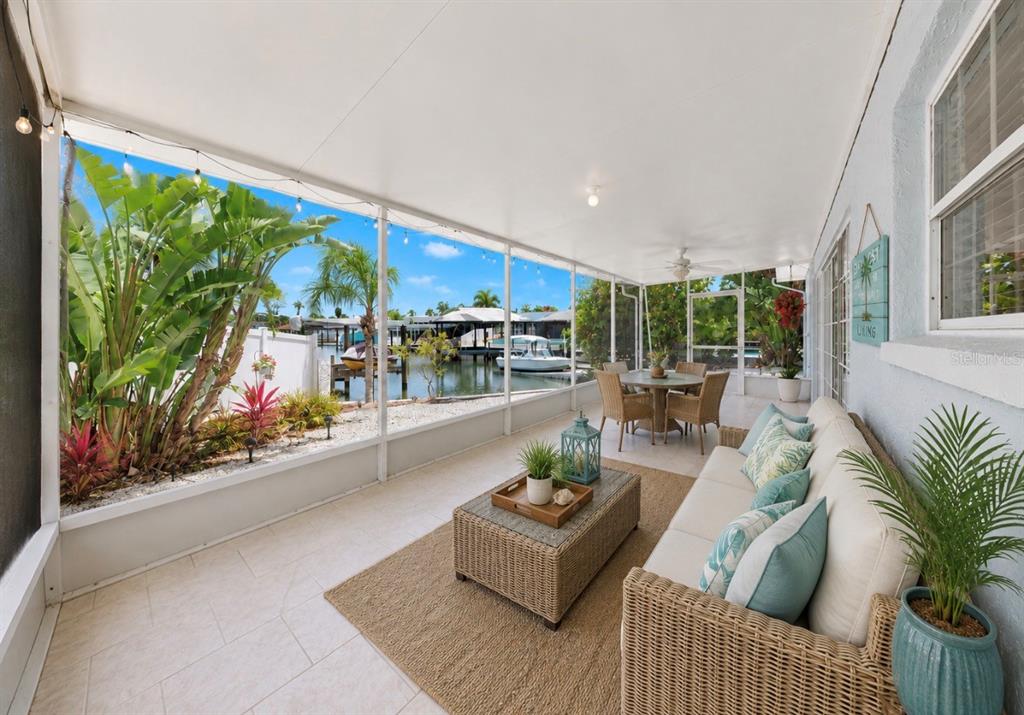 A screened-in patio features wicker furniture, a tile floor, and a view of a canal — 6513 ABACO DRIVE, APOLLO BEACH, FL