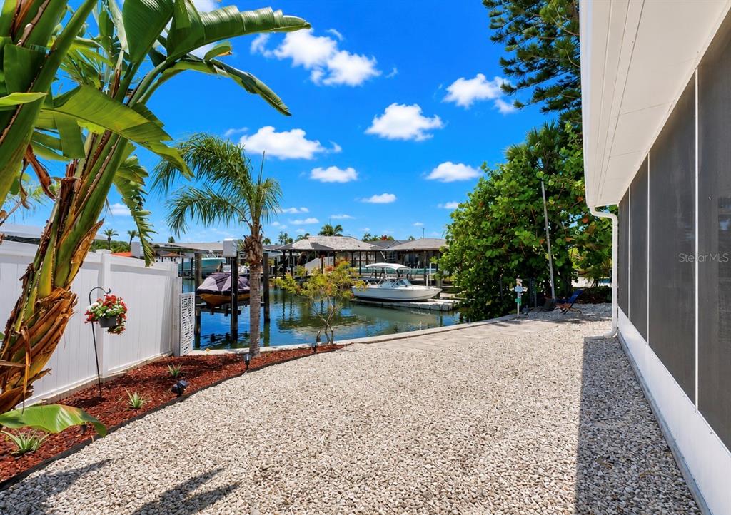 A gravel yard leads to a canal with boat docks and a white boat — 6513 ABACO DRIVE, APOLLO BEACH, FL