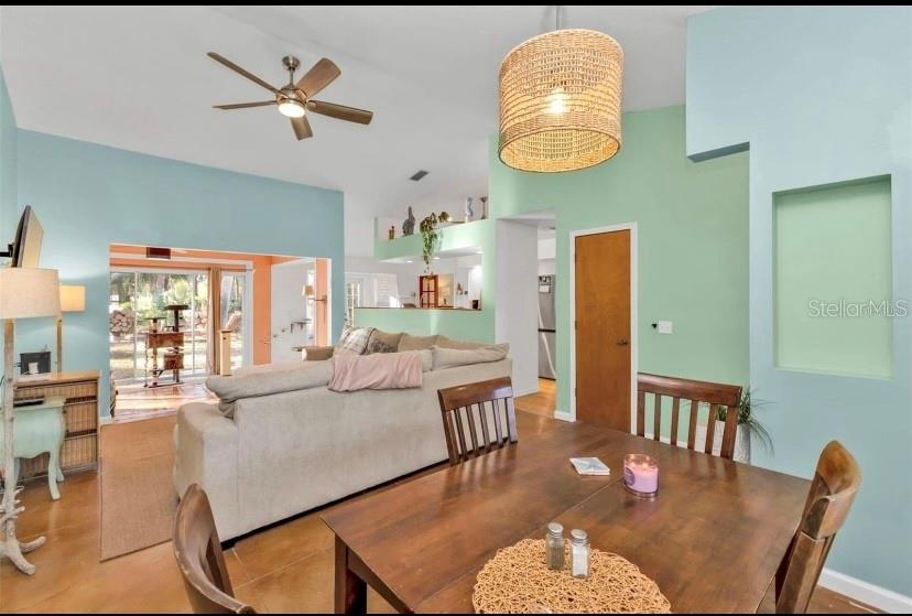 A dining area with a wooden table leads into a living room with vaulted ceilings — 3003 SIKESTON AVENUE, NORTH PORT, FL