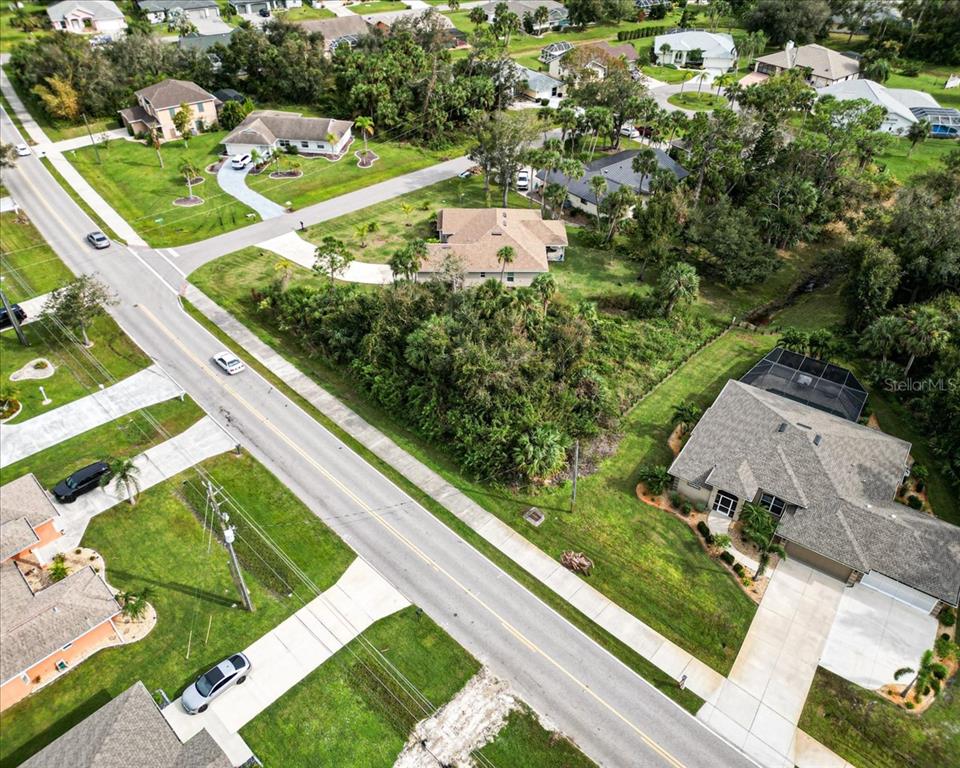 An aerial view shows a suburban street with houses, driveways, and surrounding trees — 25655 DEEP CREEK BOULEVARD, PUNTA GORDA, FL