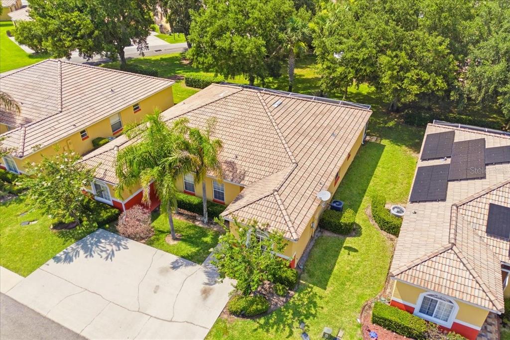 An aerial view shows a tan house with a tiled roof, palm trees, and driveway — 157 OCEAN BLUFF DRIVE, POINCIANA, FL