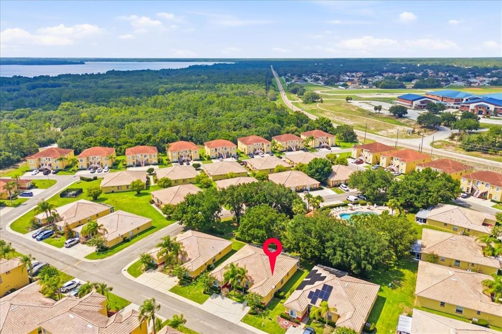 An aerial view shows a residential neighborhood of yellow houses with tiled roofs and trees — 157 OCEAN BLUFF DRIVE, POINCIANA, FL