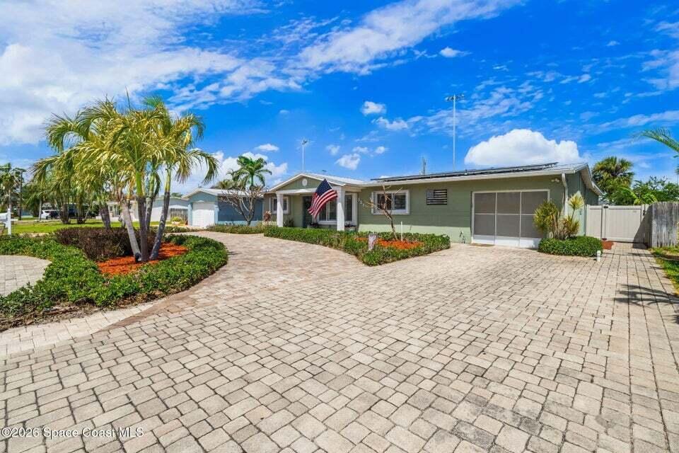 A single-story house with a paved driveway, palm trees, and an American flag — 121 Algonquin Terrace, Indian Harbour Beach FL 32937, INDIAN HARBOUR BEACH, FL