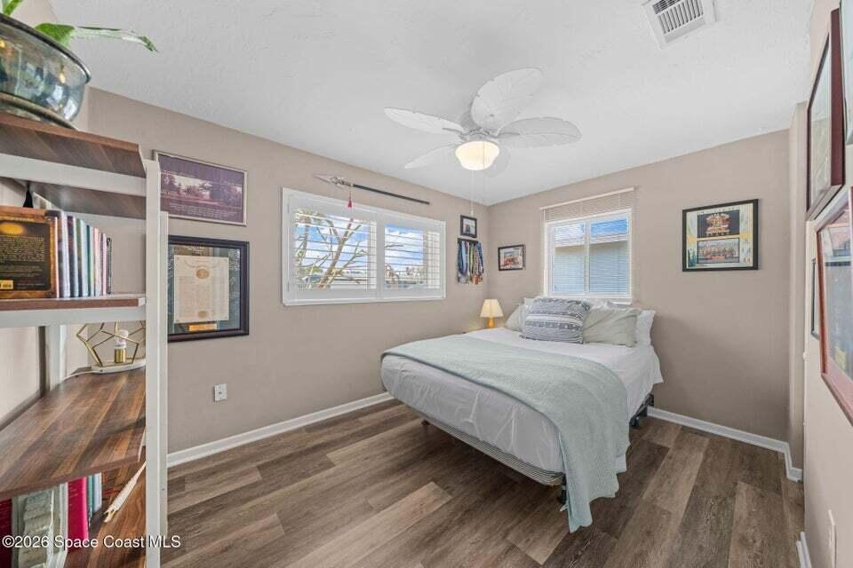 A bedroom features wood-look flooring, a ceiling fan, and a bed with light bedding — 121 Algonquin Terrace, Indian Harbour Beach FL 32937, INDIAN HARBOUR BEACH, FL