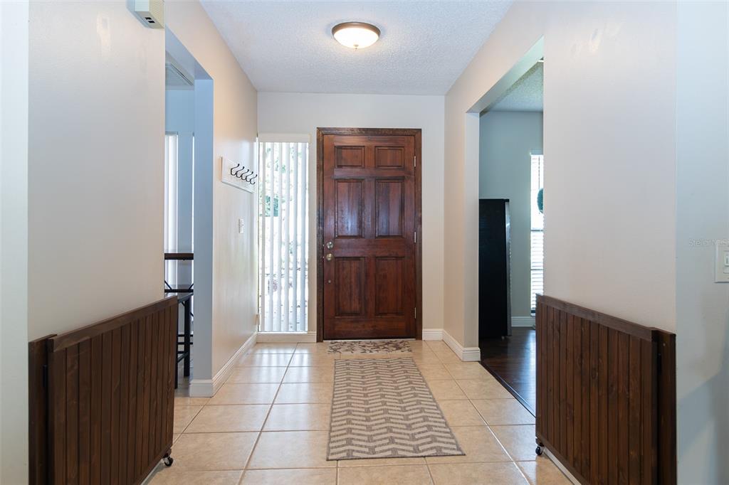 A tiled entryway features a wooden front door, a runner rug, and two wooden gates — 1005 TRANQUIVIEW LANE, VALRICO, FL