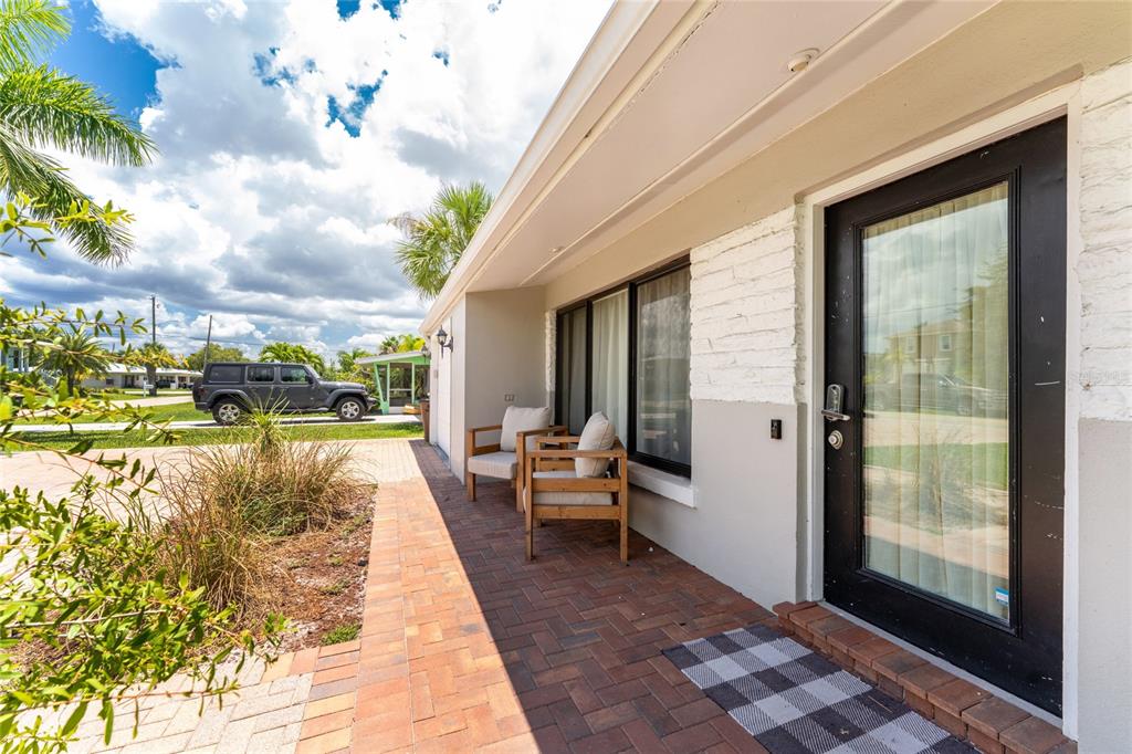 A brick patio leads to a front door with a black frame and two chairs — 409 W ANN STREET, PUNTA GORDA, FL