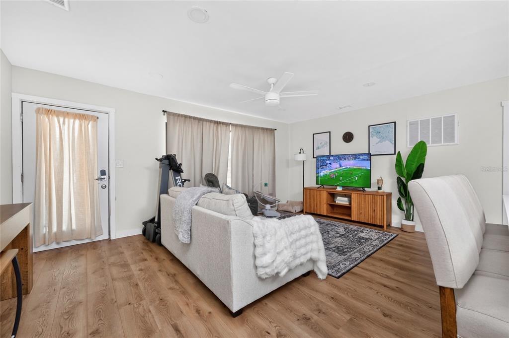 A living room features light wood flooring, a sofa, a television, and a ceiling fan — 409 W ANN STREET, PUNTA GORDA, FL
