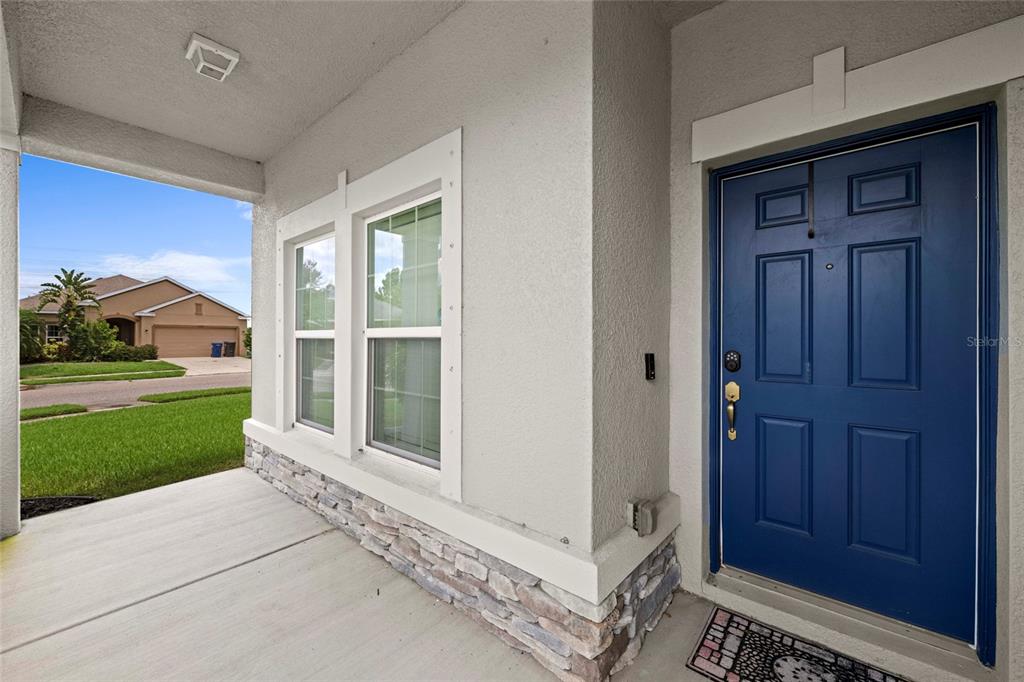 A covered front porch features a blue door, stone veneer siding, and two windows — 10816 79TH STREET E, PARRISH, FL