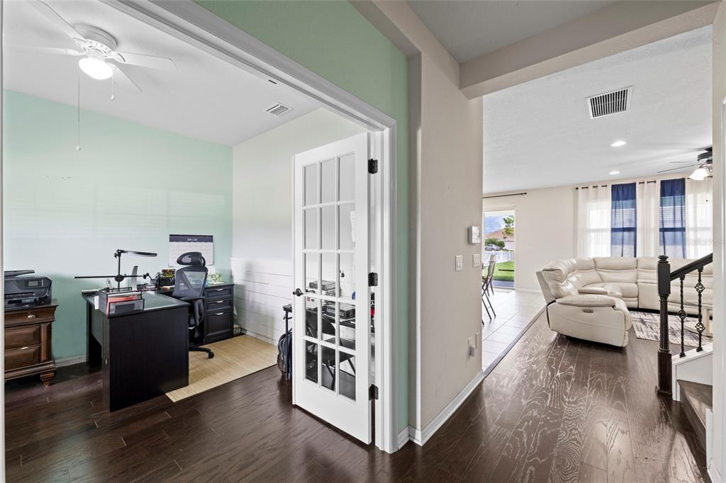 A home office with dark wood floors and French doors opens into a bright living area — 10816 79TH STREET E, PARRISH, FL