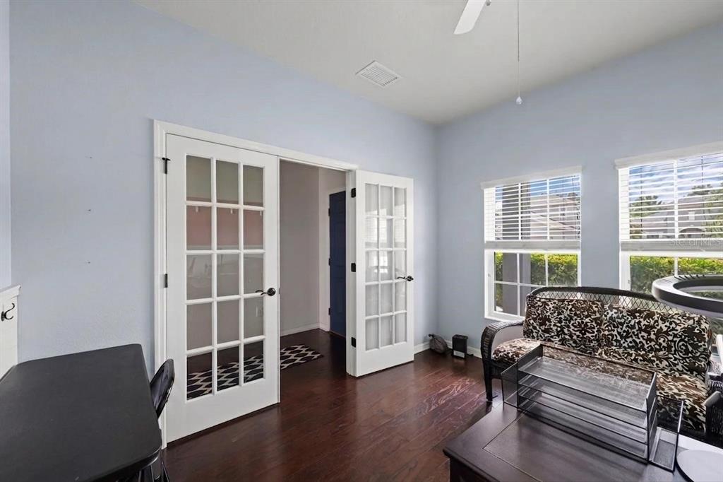 A room with light blue walls, dark wood floors, and white French doors — 10816 79TH STREET E, PARRISH, FL