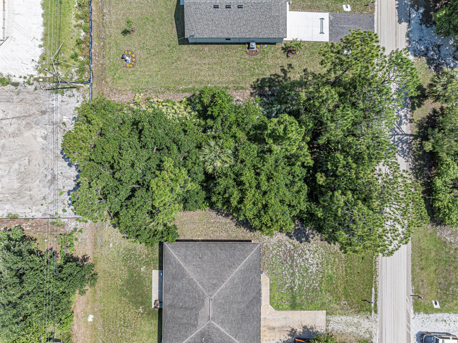 An aerial view shows a house with a gray roof surrounded by trees and grass — 8566 105th Avenue, Vero Beach FL 32967, VERO BEACH, FL