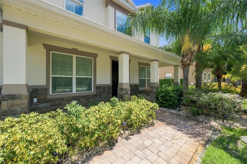 A paved walkway leads to the covered front porch of a two-story house with stone accents — 19902 WELLINGTON MANOR BOULEVARD, LUTZ, FL